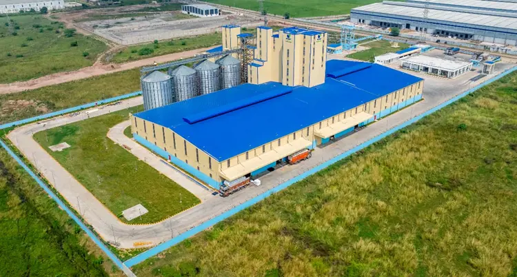 De Heus India modern animal feed mill with silos, production plant, and truck loading area.