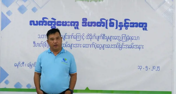 a man is standing in front of a backdrop at the event about myanmar earthquake support program.